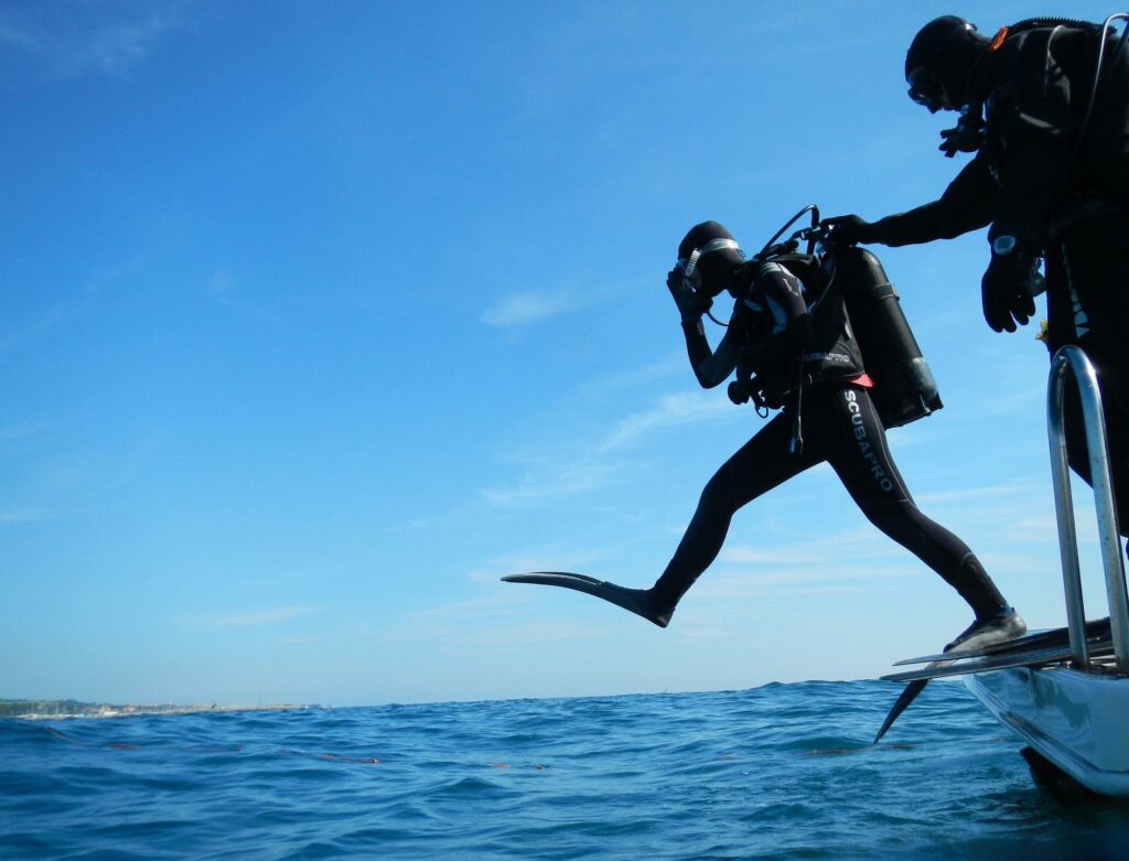 Plongeur de Triton Diving effectuant une mise à l'eau par un pas de géant dans la mer bleue de Playa del Carmen, l'aventure de plongée commence.