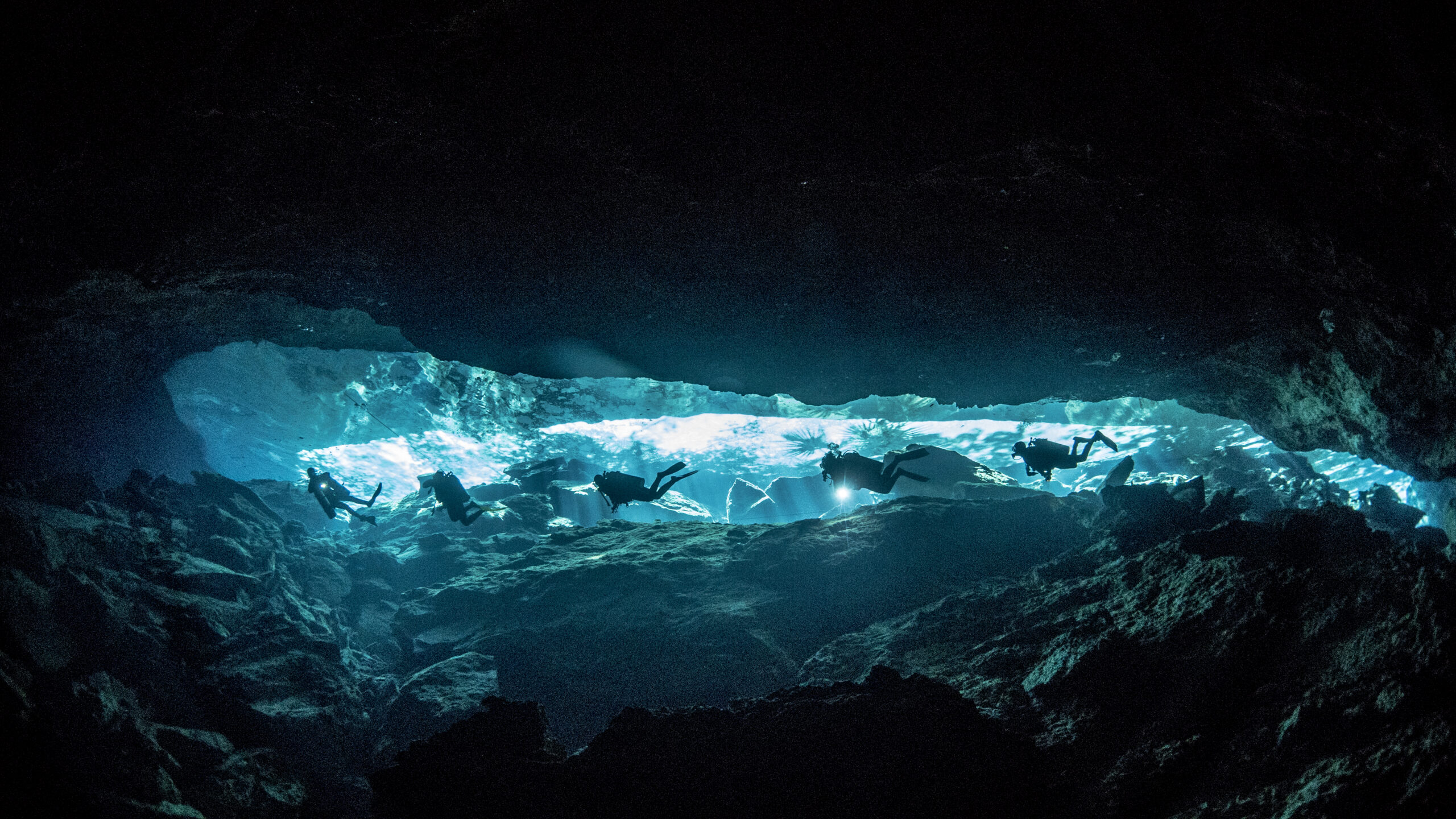 Triton Diving : Plongeurs éclairés par la lumière naturelle dans les eaux cristallines du Cénote Chac Mool