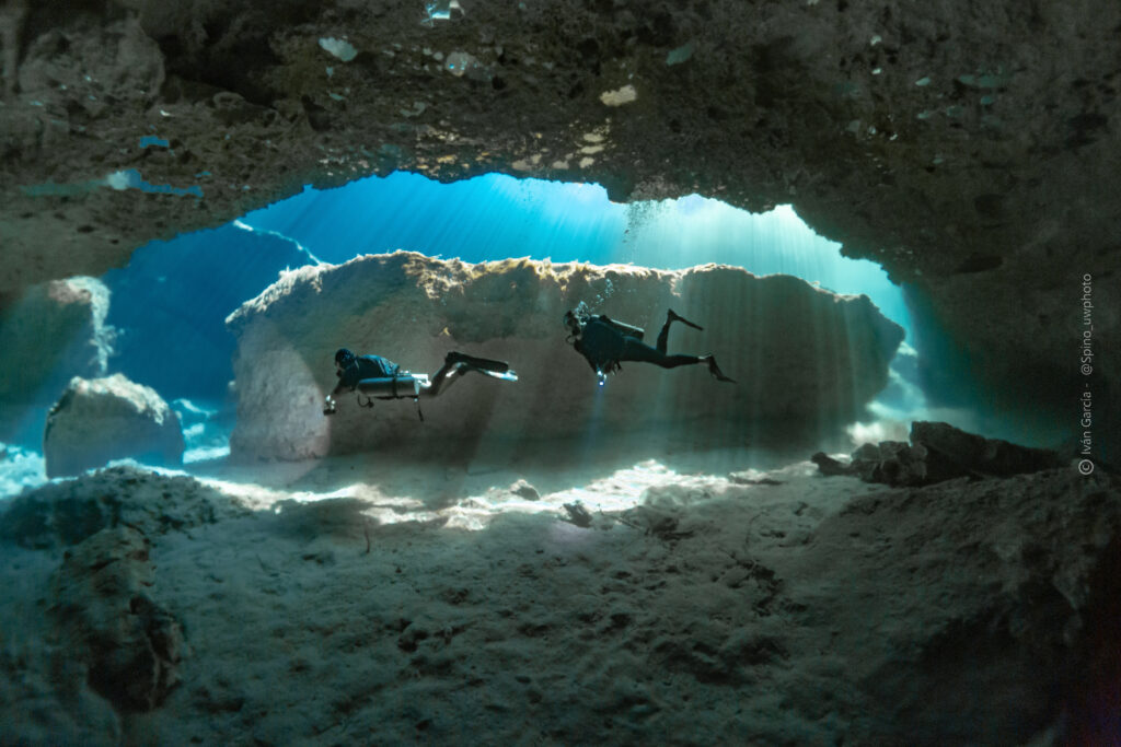 Triton Diving silhouette against the radiant sunbeams piercing through Casa Cenote's water