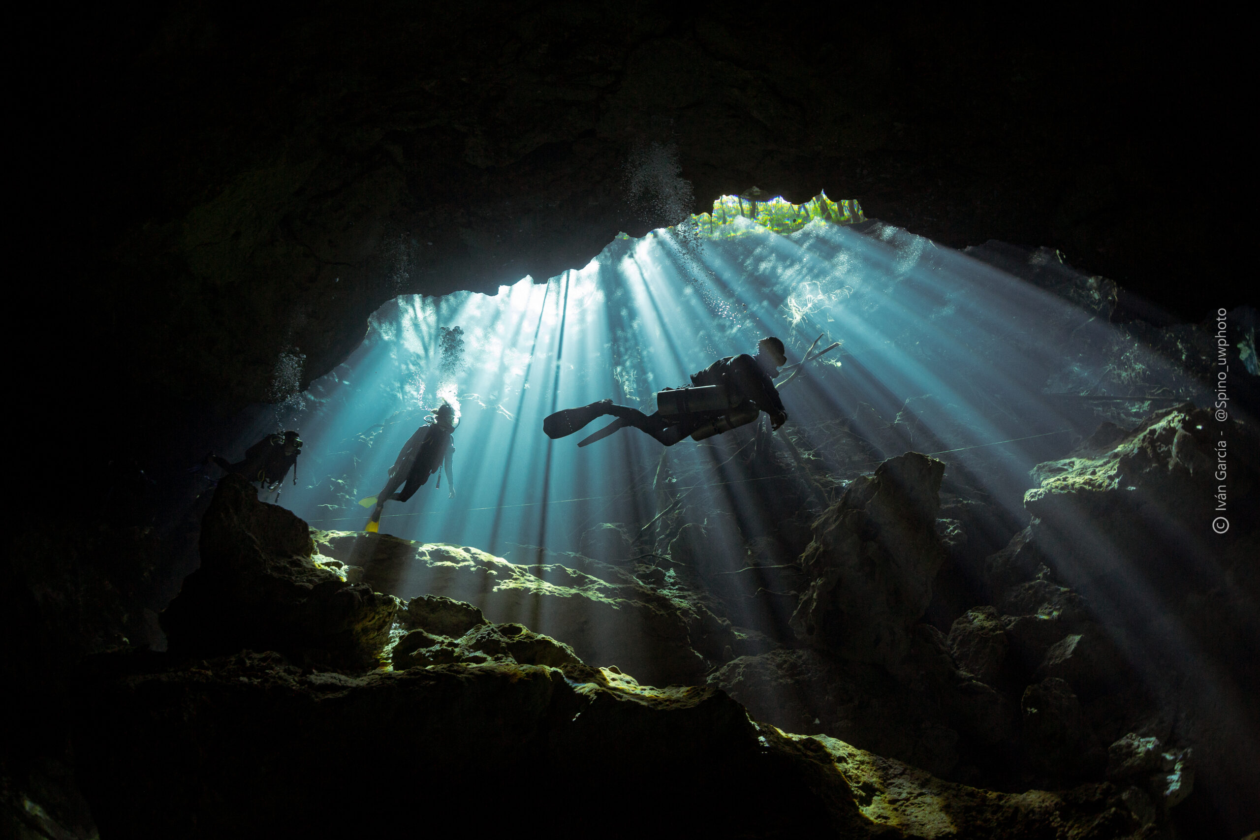 Plongeurs sous-marins de Triton Diving immergés dans les rayons lumineux radieux à l'intérieur du Cénote Chac Mool