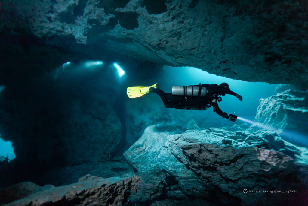 Aventurier de Triton Diving avec des palmes jaunes vives explore la caverne sous-marine du Cénote Chikin Ha