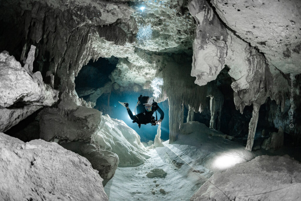 Explorateur de Triton Diving avec palmes en l'air nageant à travers les passages caverneux du Cénote Dos Ojos