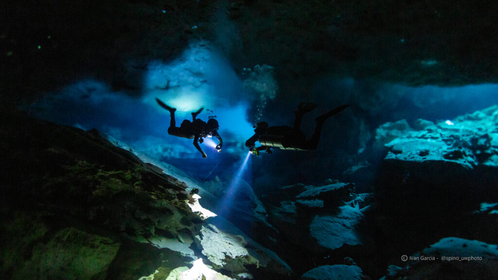 Aventuriers de Triton Diving éclairés par un rayon de lumière dans les profondeurs du Cénote Jardin del Eden