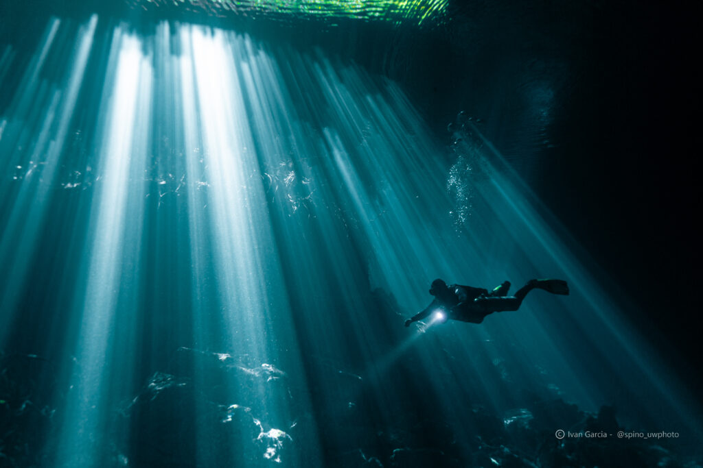 Explorateur de Triton Diving dans les faisceaux sous-marins radieux du Cénote Jardin del Eden