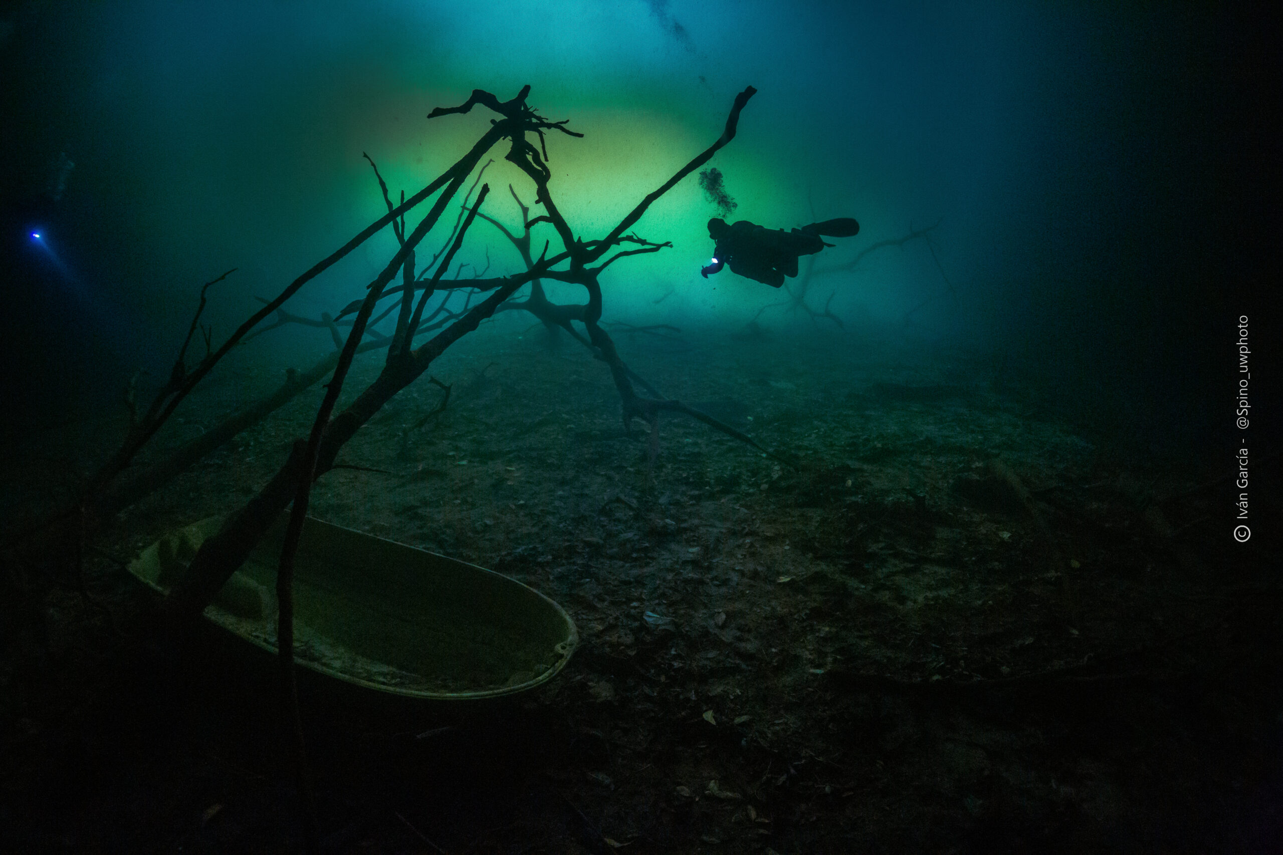 Explorateur de Triton Diving survole les vestiges submergés du Cenote Orquídea, avec un bateau englouti mystérieux au premier plan