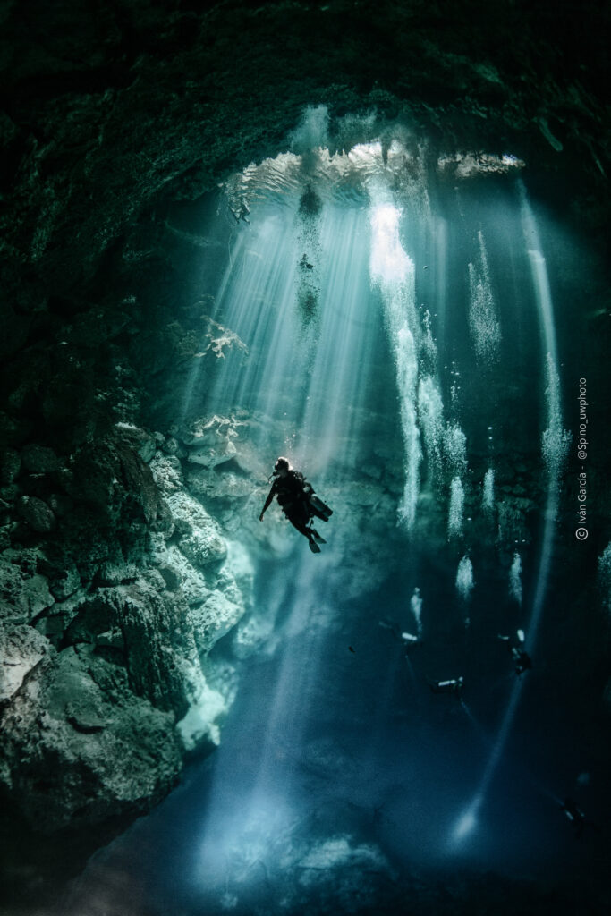 Explorateur de Triton Diving capturé dans le projecteur naturel des rayons de soleil du Cenote The Pit