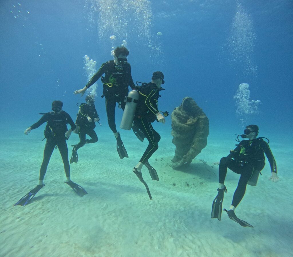 Groupe de Triton Diving vivant un baptême de plongée autour de la statue sous-marine de la Vierge à la Cueva del Pargo de Playa del Carmen