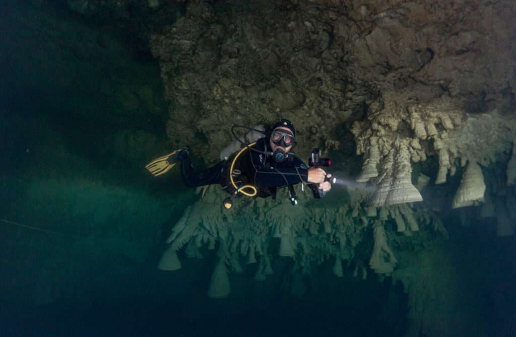 Diver with a torch near the Hells Bells in Cenote Zapote
