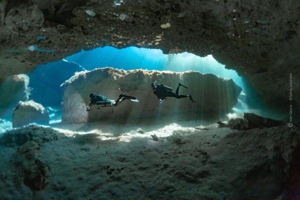 Silhouette de Triton Diving contre les rayons radieux du soleil perçant à travers l'eau de Casa Cenote